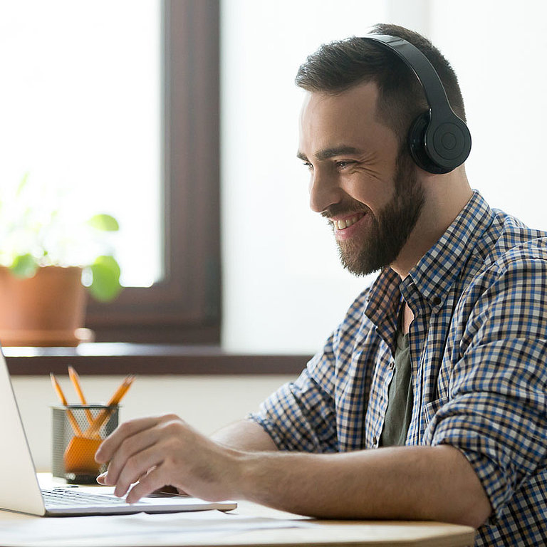 Zertifizierungsberatung Mann sitzt am Tisch und arbeitet am Laptop